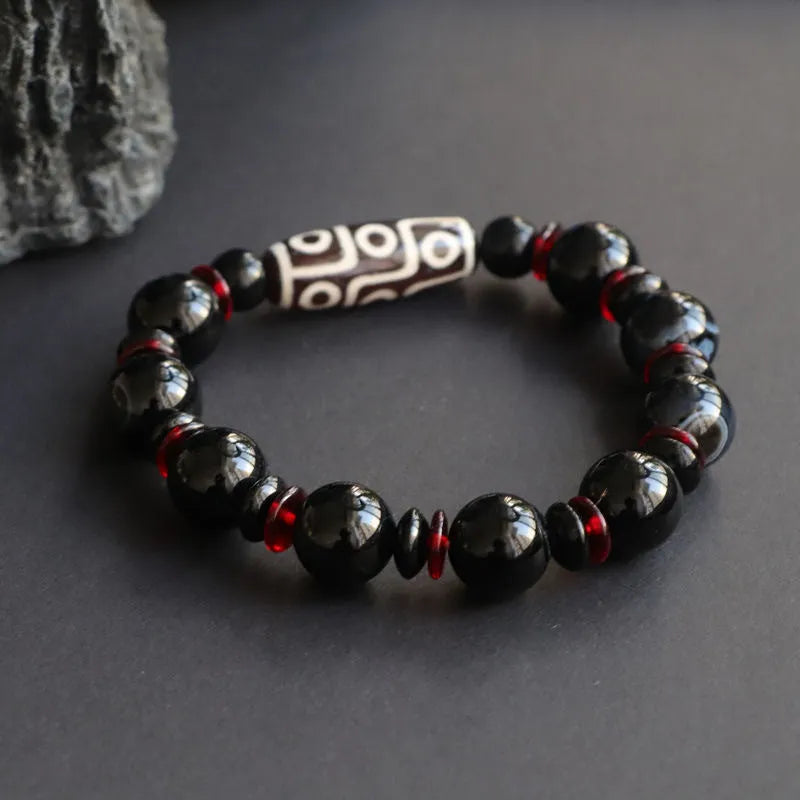 Close-up of a hand-woven black agate bracelet with 11mm geometric beads featuring traditional dzi patterns.