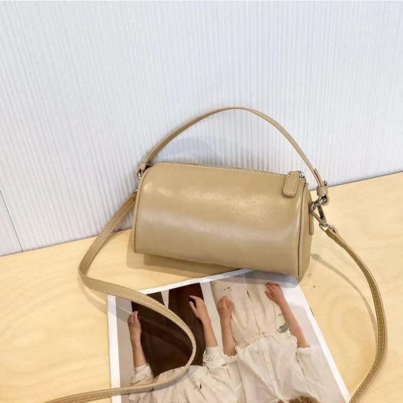 Soft genuine leather cylindrical crossbody bag for mobile phones, shown in a street style with visible stitching.