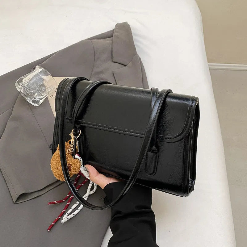 Brown women's structured square PU leather shoulder bag with a detachable tassel pendant and double straps.
