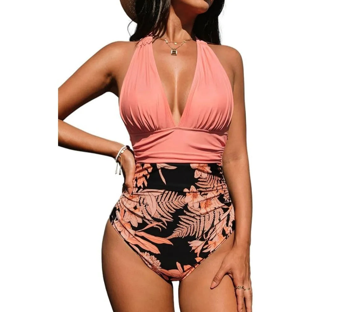 Women's pink floral one-piece halter neck swimsuit on a mannequin, showing backless design.
