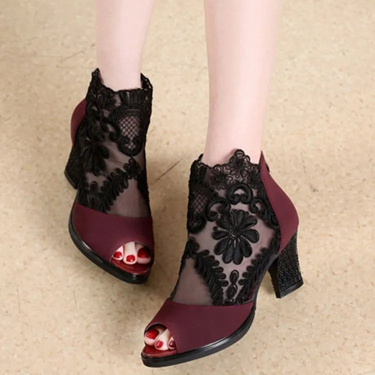 Black lace gladiator sandals with a square high heel and peep toe on a woman's foot