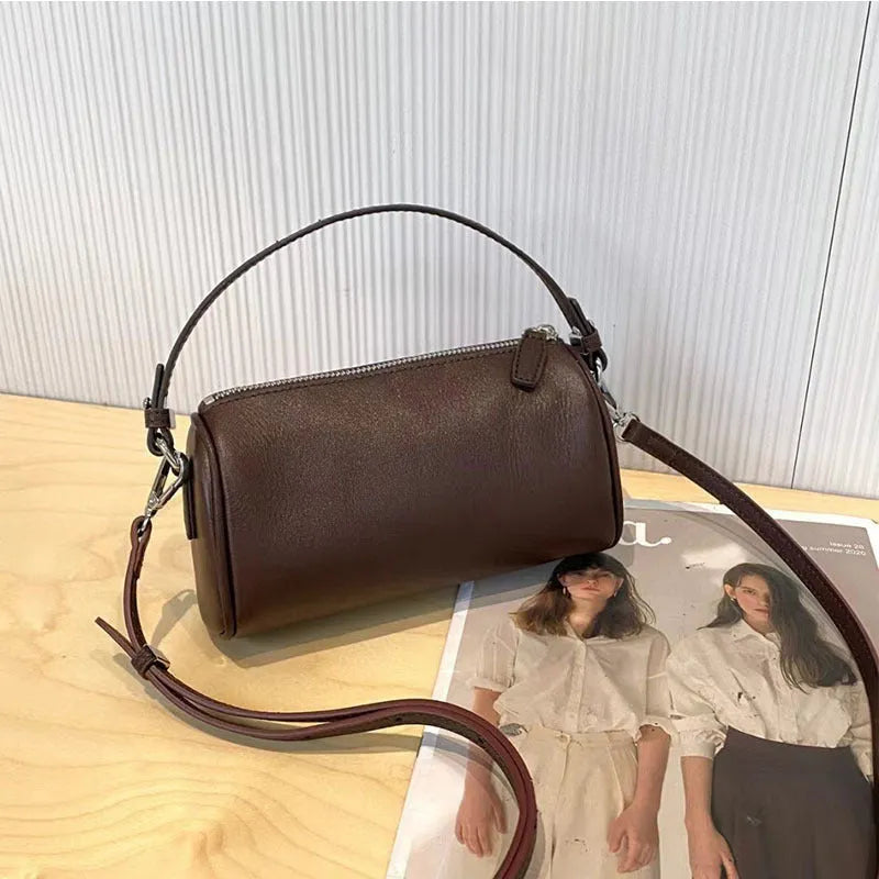 Soft genuine leather cylindrical crossbody bag for mobile phones, shown in a street style with visible stitching.