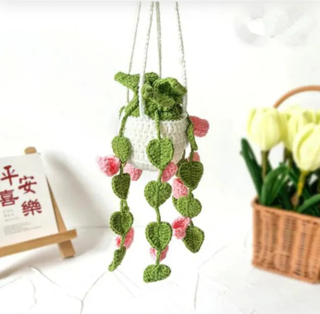 Green and white knitted wool car plant decoration with hanging rope on car dashboard