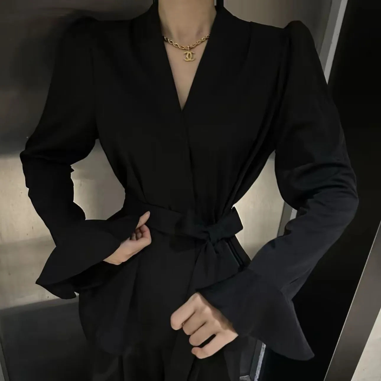 Woman wearing a wine red long sleeve shirt with an irregular French collar, bell sleeves, and a tie front.