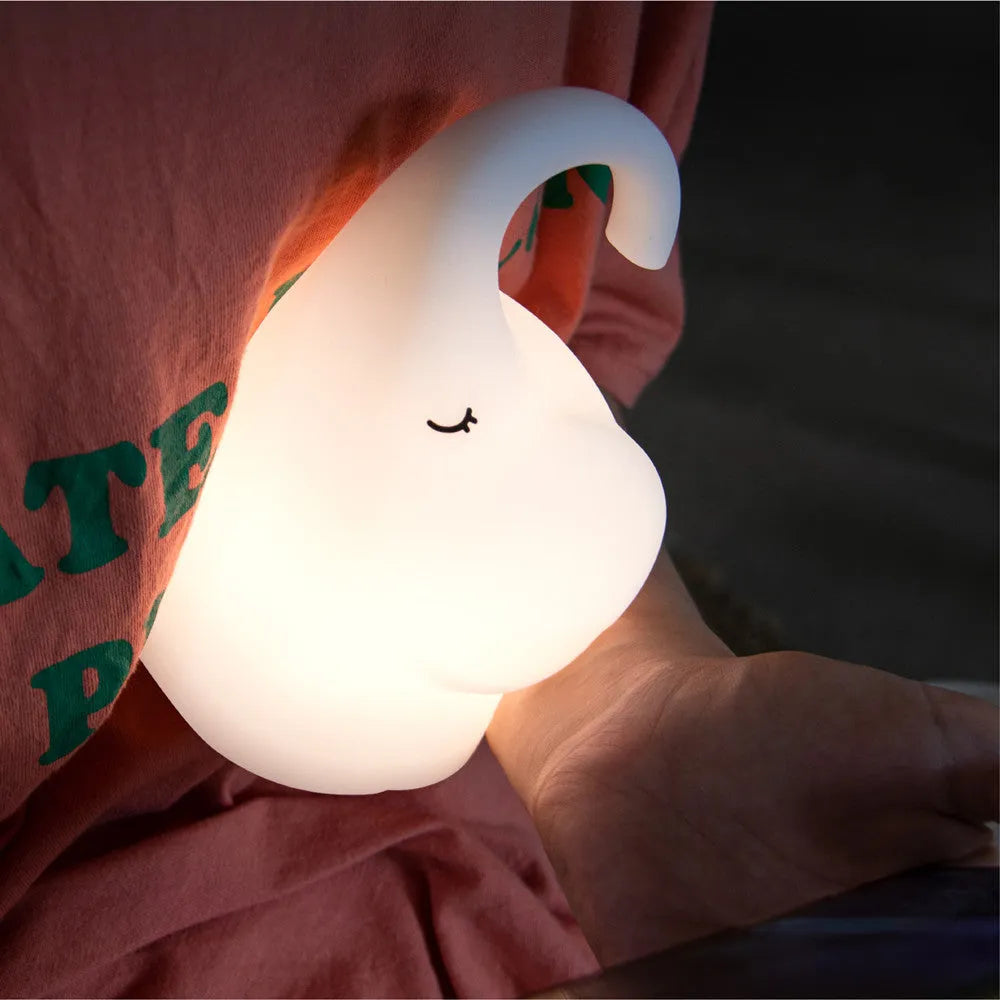 DOMI soft silicone elephant night light on a bedside table emitting warm white glow