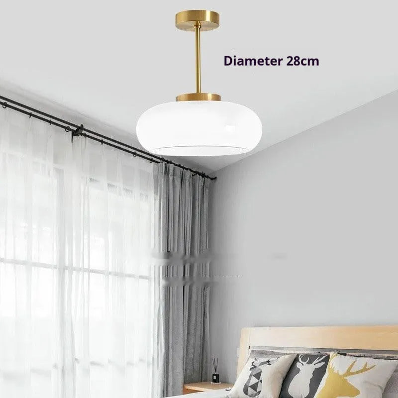 Three-headed Bauhaus pendant light with milky white glass egg tart shades hanging from a ceiling.