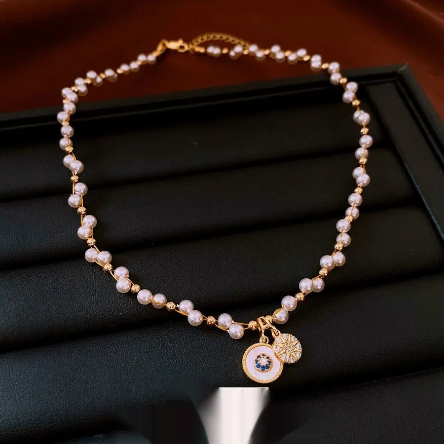 Gold electroplated clavicle necklace with round geometric pendant containing zircon inlay and imitation pearl centrepiece