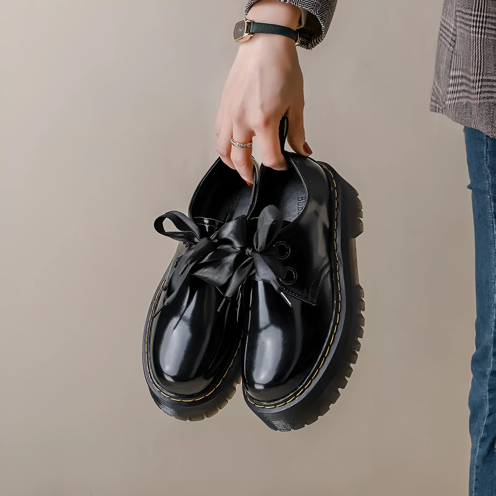 Women's black thick soled lace-up shoes with ribbon detail on a white background