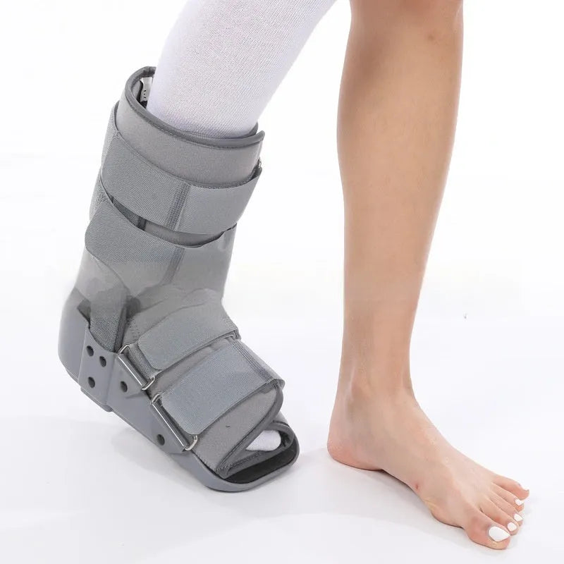 Grey Achilles tendon rehabilitation boot with aluminium side struts and a rubber sole, shown on a foot.