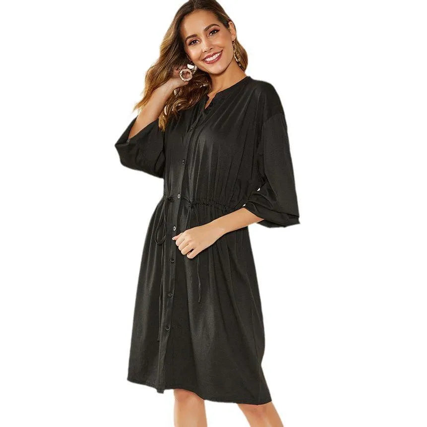 A woman wearing a solid colour midi dress with an elastic waist, long sleeves, and a loose belt.