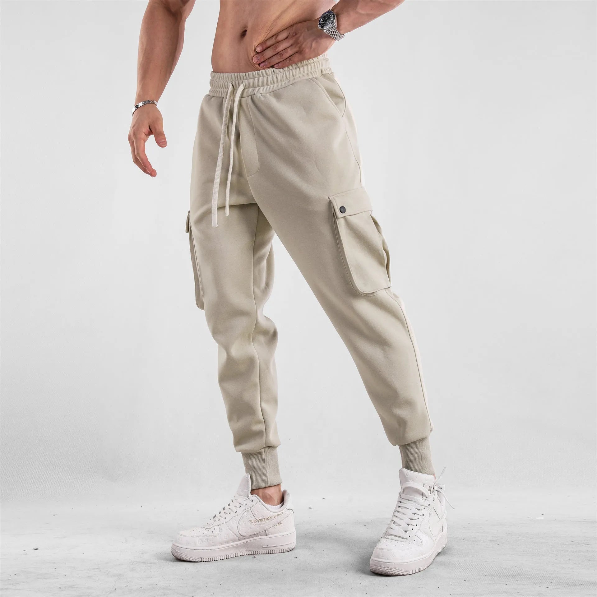 Man wearing loose light grey cotton trousers with ankle tie and multiple pockets, style of American sports leisure wear.