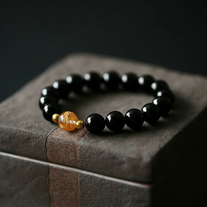 Geometric unisex bracelet with black obsidian agate beads, white crystal beads, and a golden dragon crystal focal bead.