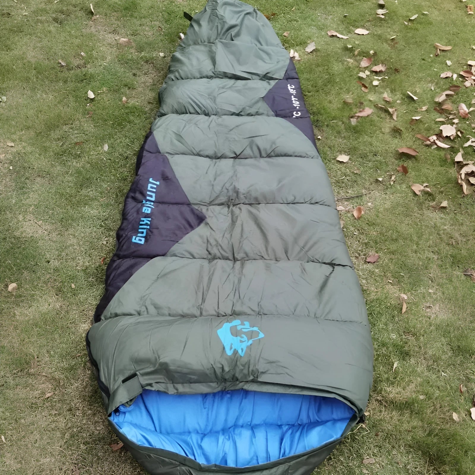 Outdoor cotton sleeping bag in Army Green with its compression storage sack laid beside it.