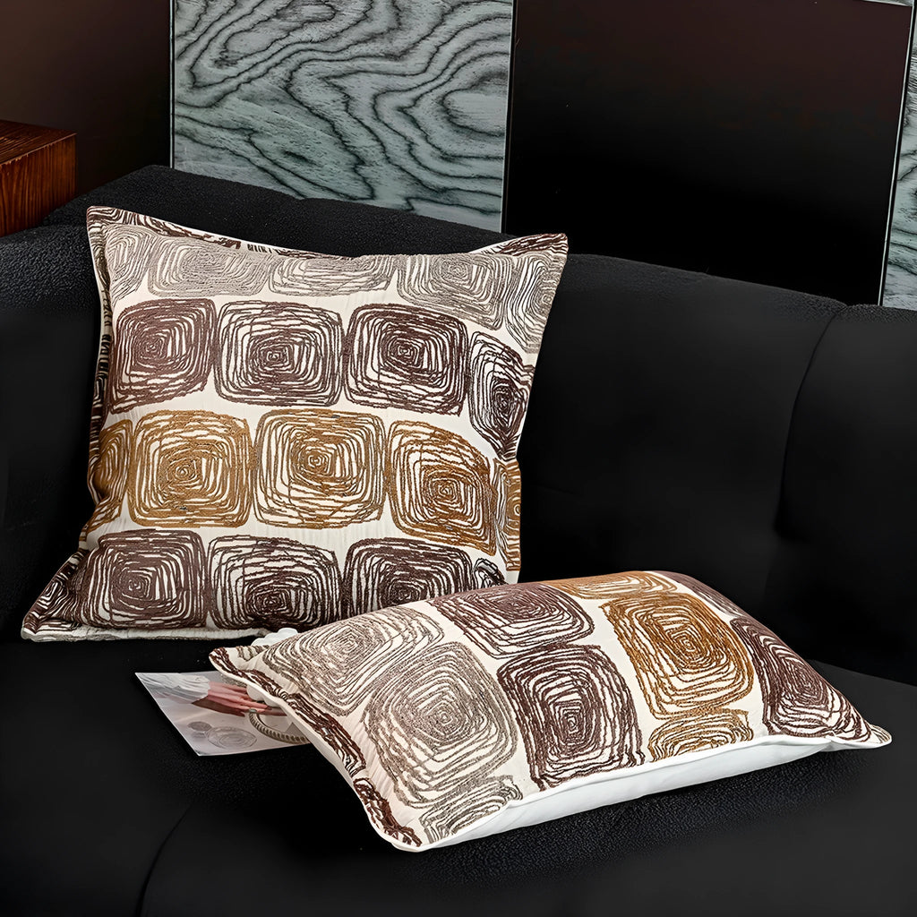 Cream and coffee coloured abstract coil pattern on two pillow sizes: a square cushion and a rectangular bolster.