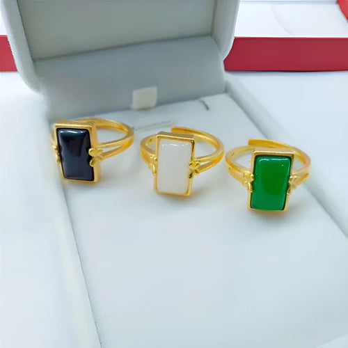 Adjustable brass gold-plated ring with a central green artificial gemstone on a finger.
