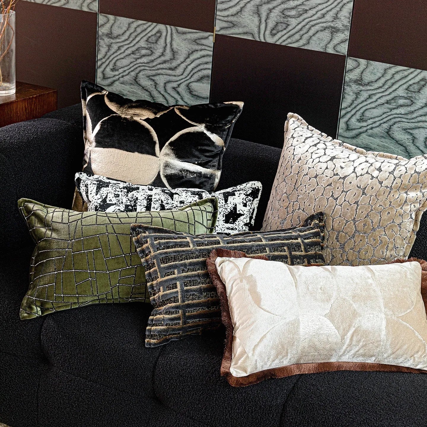 Black and gold abstract patterned flannel cushion in square and bolster sizes on a grey sofa.