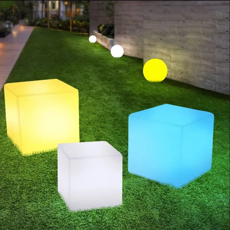 White square LED cube stool light for outdoor use, showing modern design with solar panel or charging port.