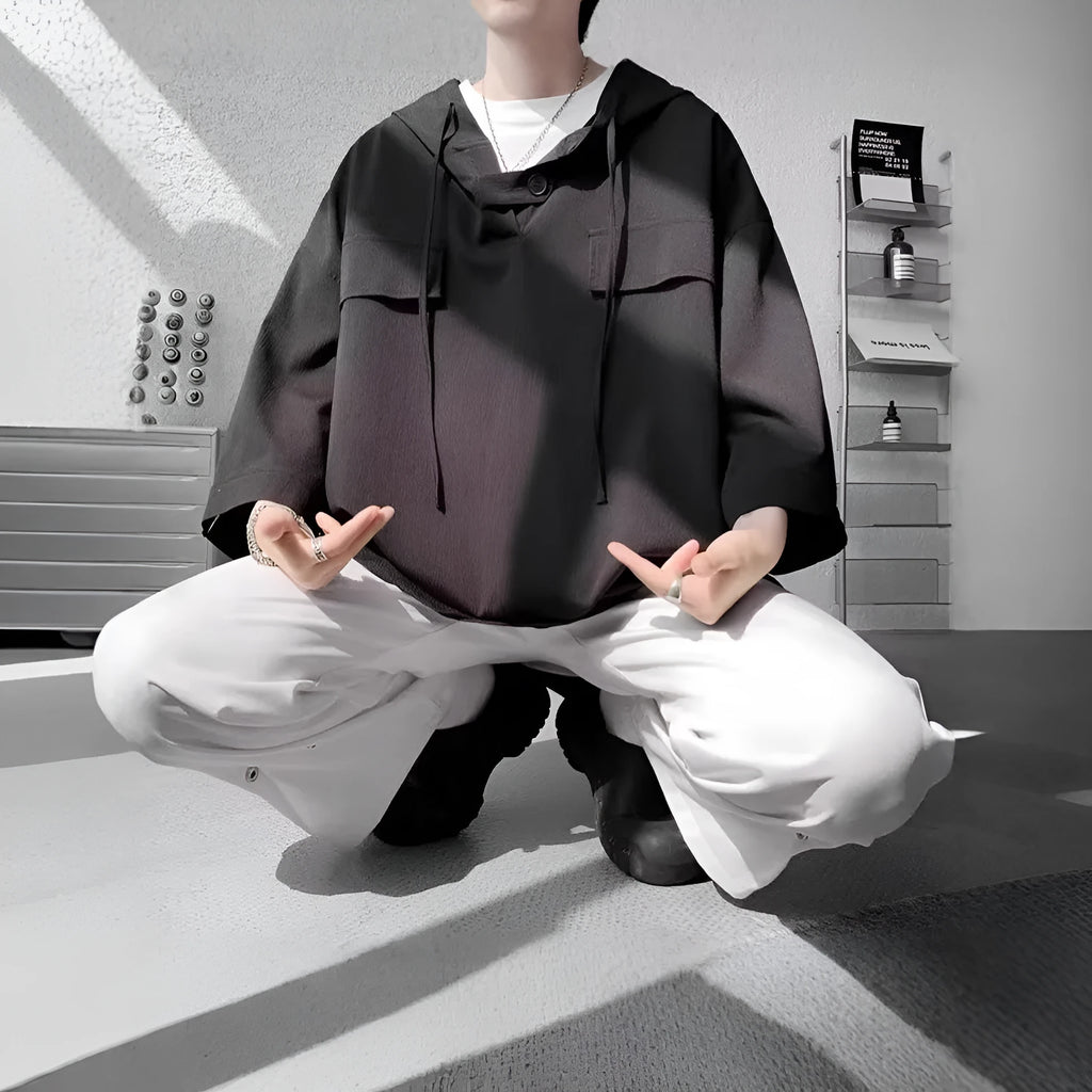 Man modelling a loose grey hooded short sleeve t-shirt, showing the pullover style and front design.