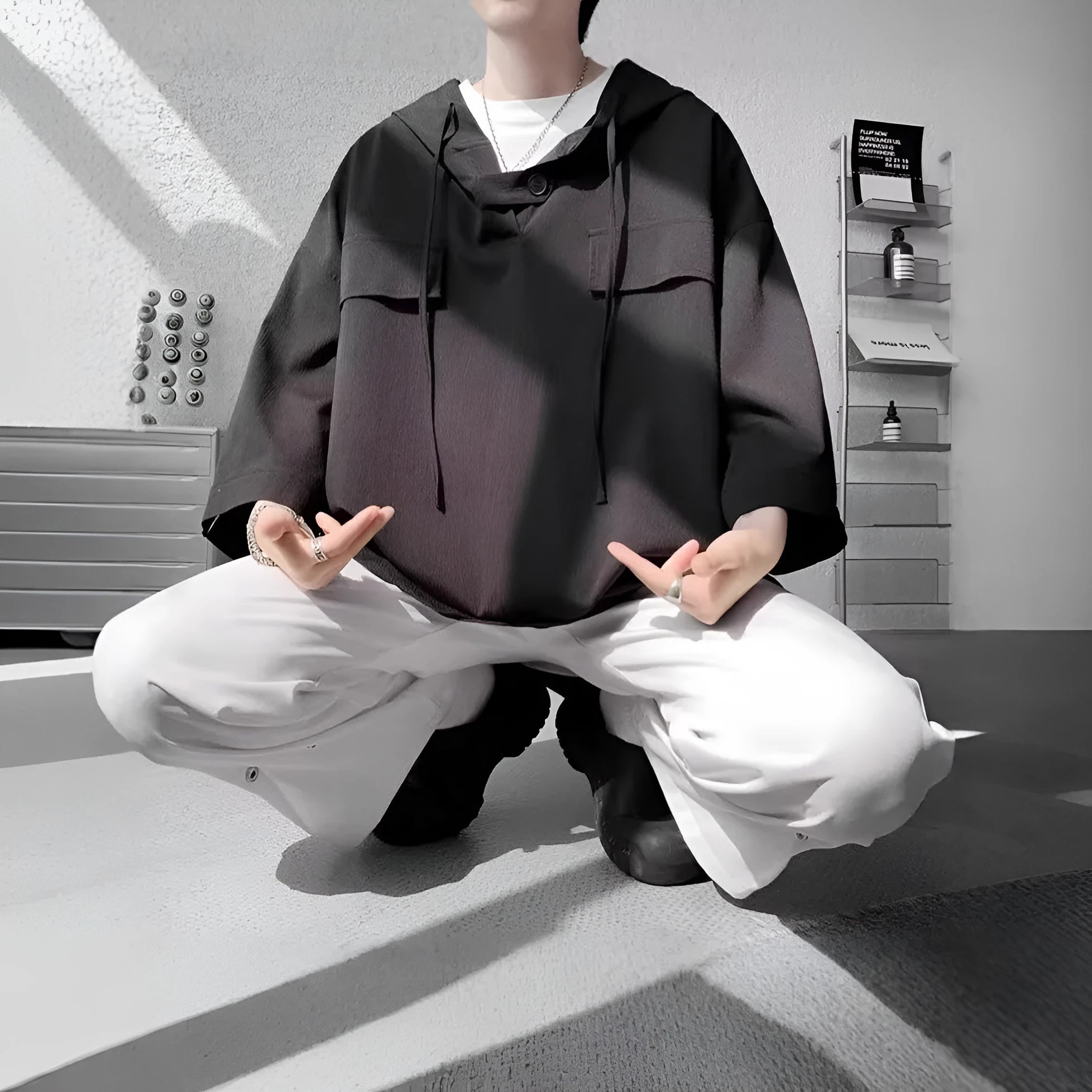 Man modelling a loose grey hooded short sleeve t-shirt, showing the pullover style and front design.