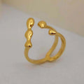 Gold or silver brass opening ring with spherical design elements on a model's finger.