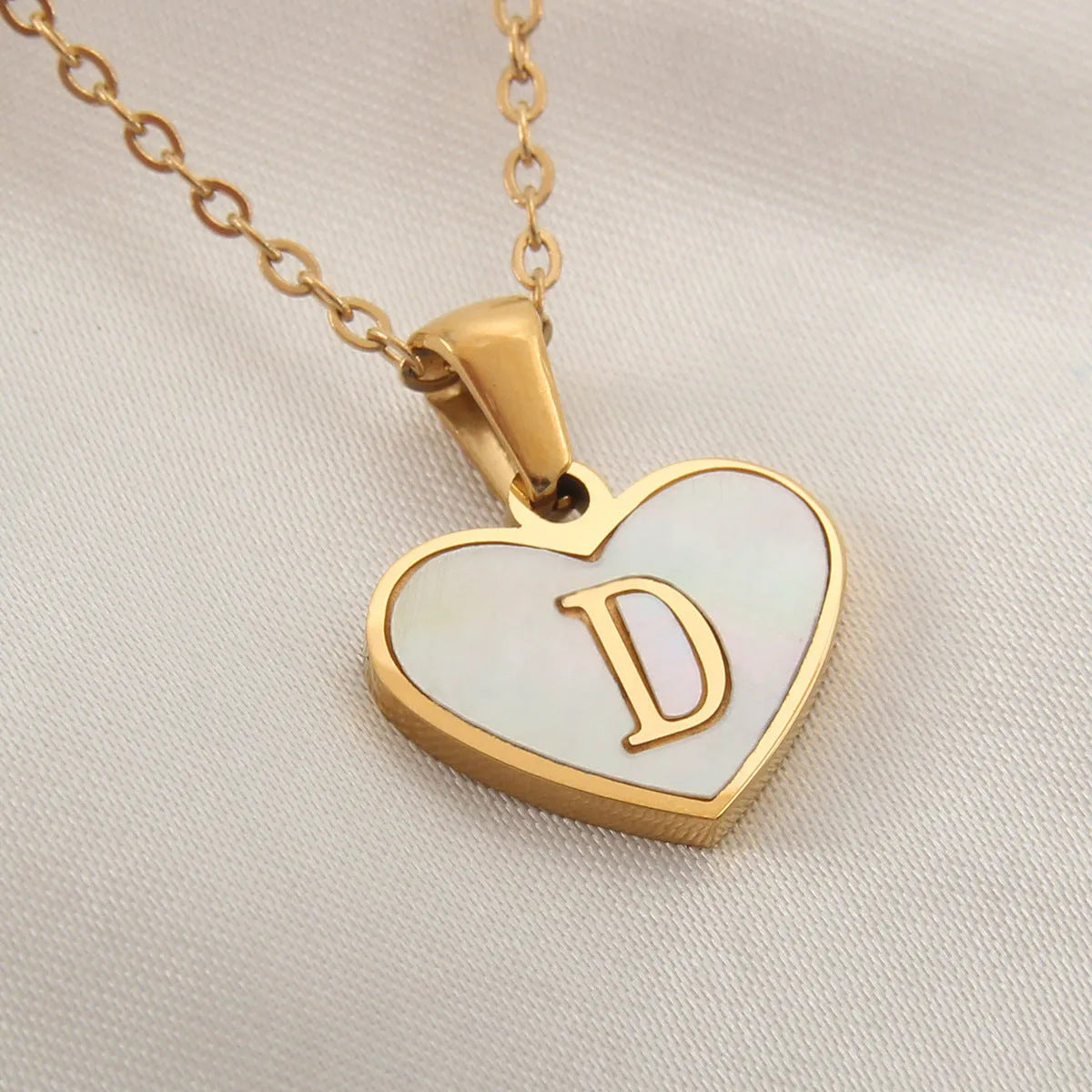 Gold-plated heart necklace with white shell pendant personalised with a letter, on an adjustable chain.