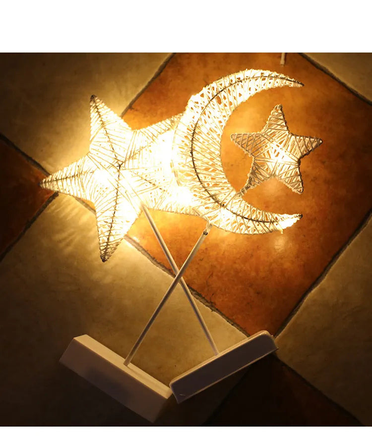 Rattan and copper wire LED table lamp in a star, heart, or moon shape on a wooden table.