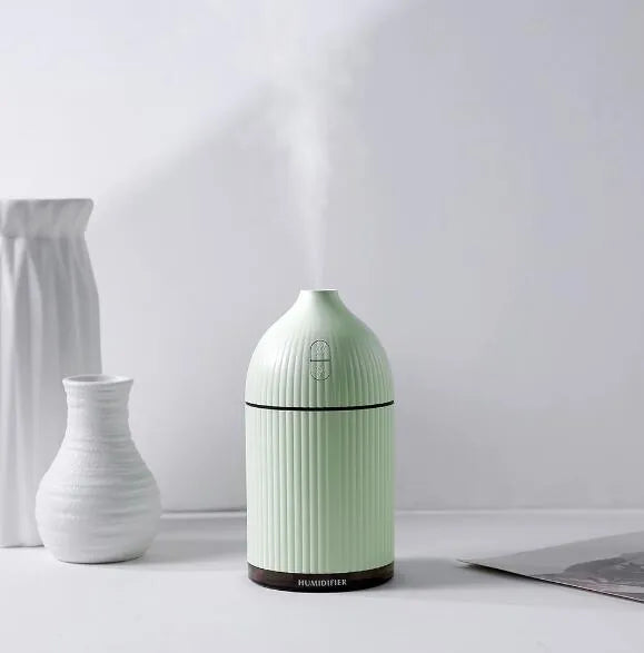 White ultrasonic aromatherapy diffuser and humidifier with LED light on a wooden surface.