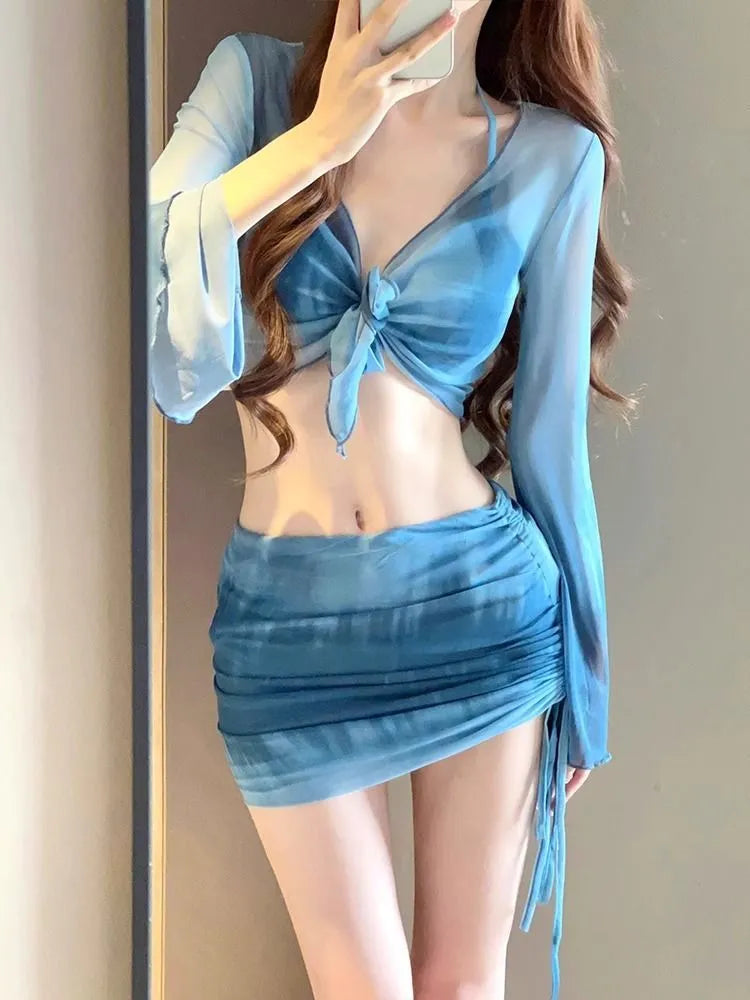 Women's blue four-piece bikini swimsuit set with shirt, bra, underwear, and skirt on hanger