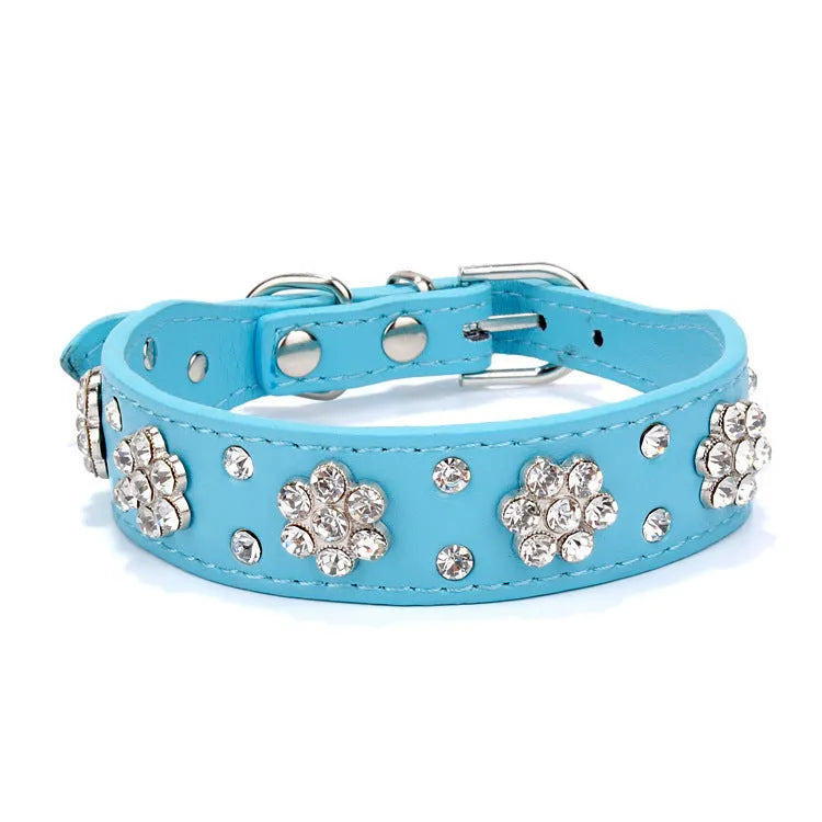 Close-up of a pink PU leather dog collar with silver rhinestone flowers and studs, showing the metal D-ring.