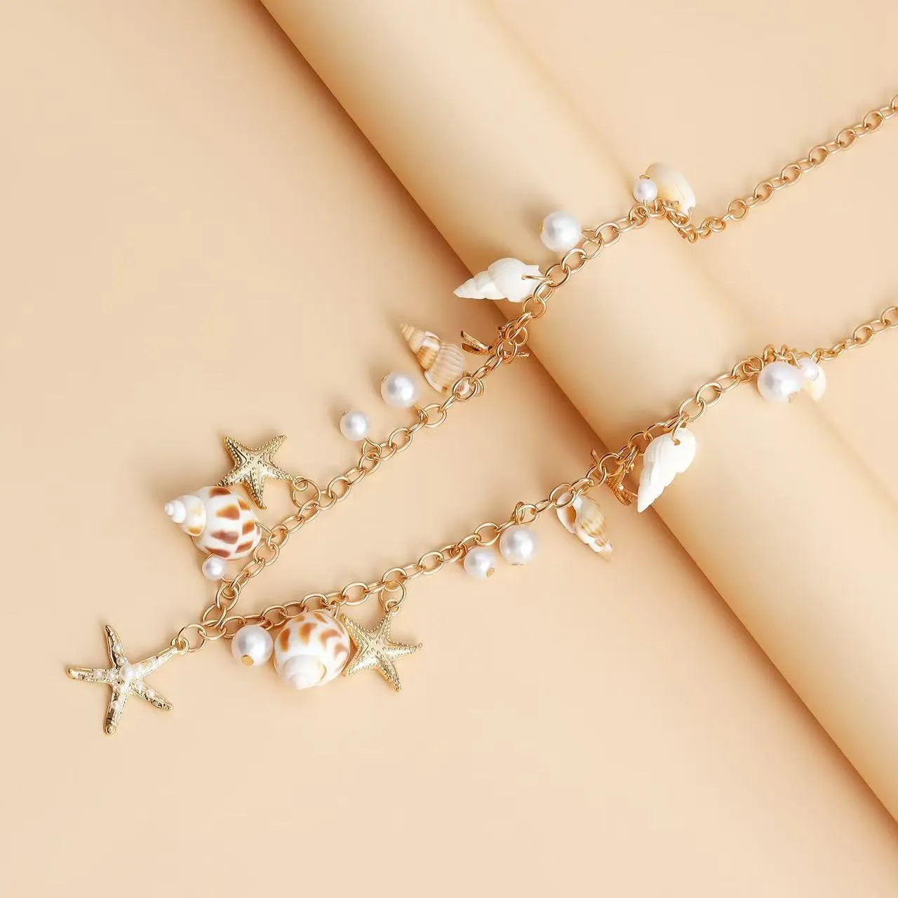 Women's silver alloy waist chain and bracelet set with star charms and beach shell pendant on white background