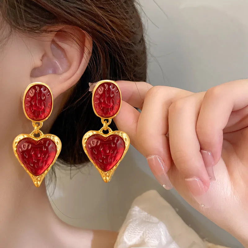 Oval-shaped love heart stud earrings with a pleated silver texture in purple, red, green, and yellow/white colours.