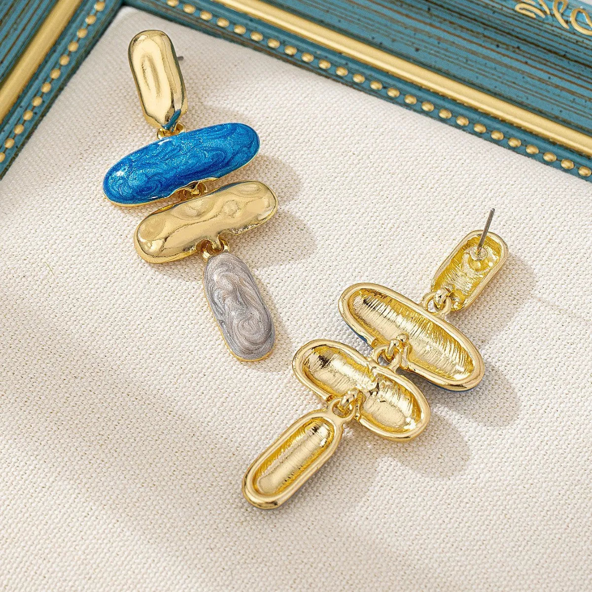 A pair of simple geometric stud earrings with a multicolour metallic finish.