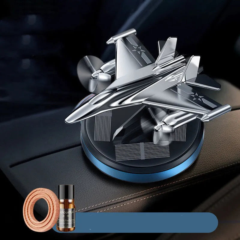 Silver solar powered rotating fighter aircraft perfume ornament on a table.