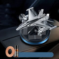 Silver solar powered rotating fighter aircraft perfume ornament on a table.