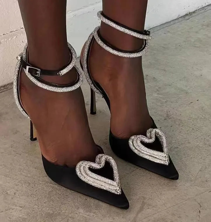 Women's pink satin sandals with heart-shaped rhinestone detail and cross-band straps on a pointed toe.