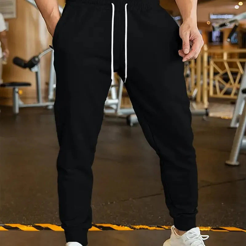 Men's loose fit linen-style trousers with a drawstring elastic waist, shown in a casual setting.