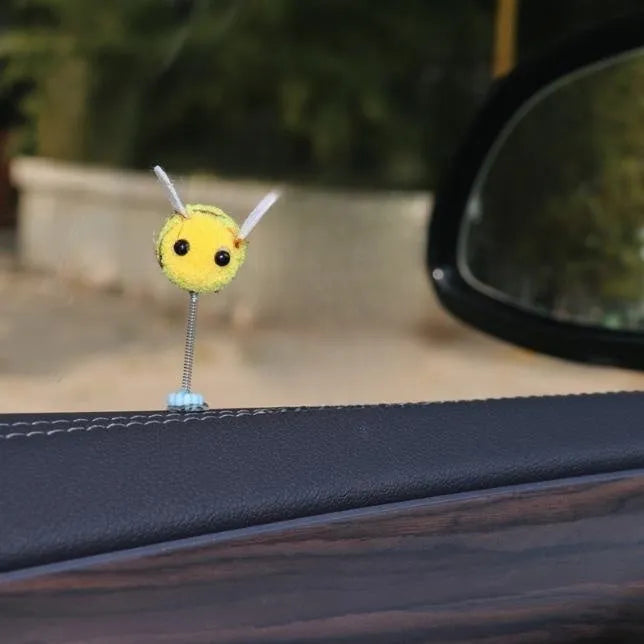 Spring-loaded bee car decoration with fur texture swinging from dashboard