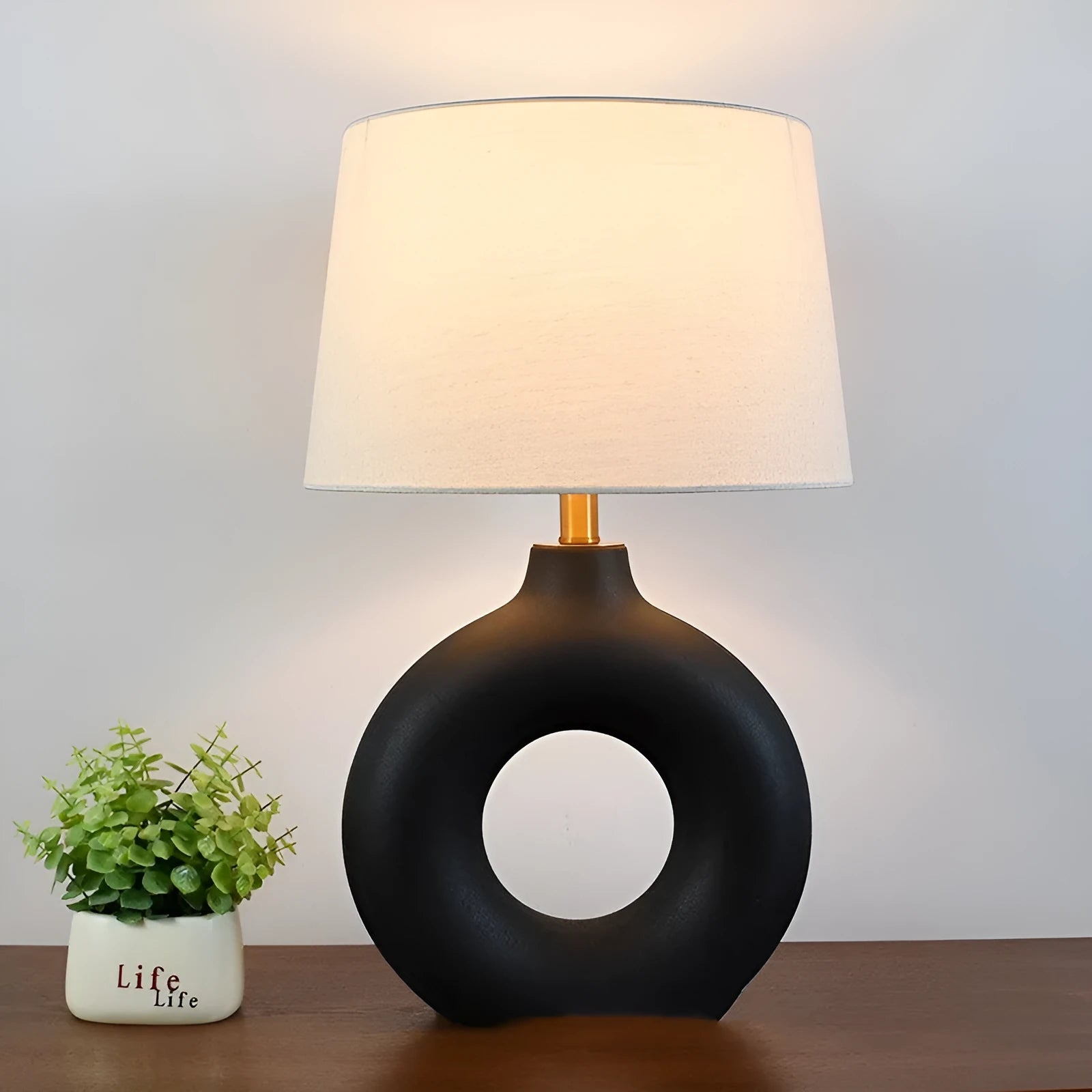 Japanese-style white ceramic table lamp with a button switch on a wooden desk.