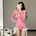 Women's long sleeve one-piece swimsuit in pink and black, made from polyester fabric.