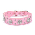Close-up of a pink PU leather dog collar with silver rhinestone flowers and studs, showing the metal D-ring.