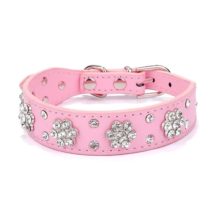 Close-up of a pink PU leather dog collar with silver rhinestone flowers and studs, showing the metal D-ring.