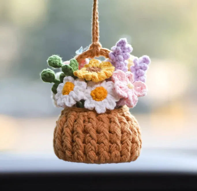 Green and white knitted wool car plant decoration with hanging rope on car dashboard