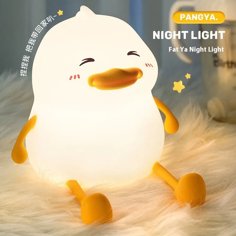 Chubby silicone pat night light on a desk holding a mobile phone, showing its compact size and soft design.