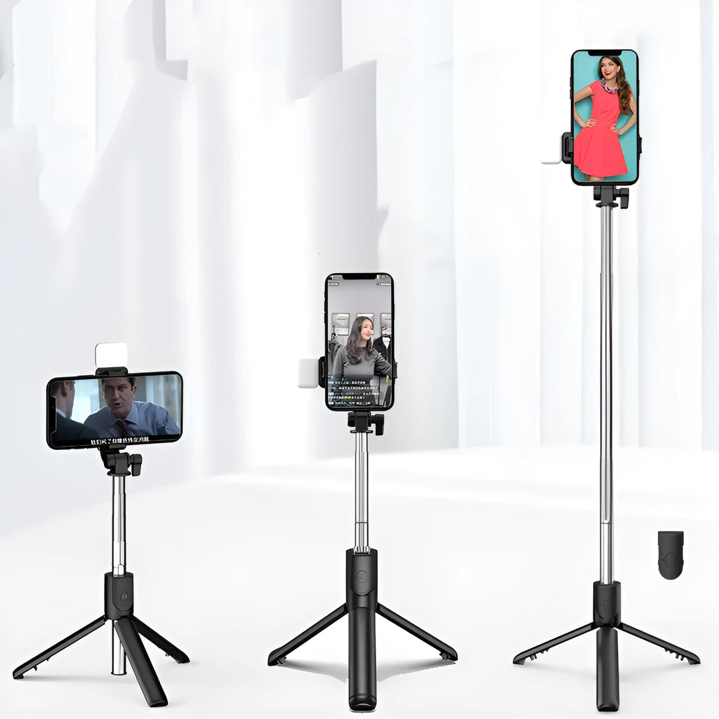 Black Bluetooth selfie stick tripod with phone holder, fill light, and remote control on a table.