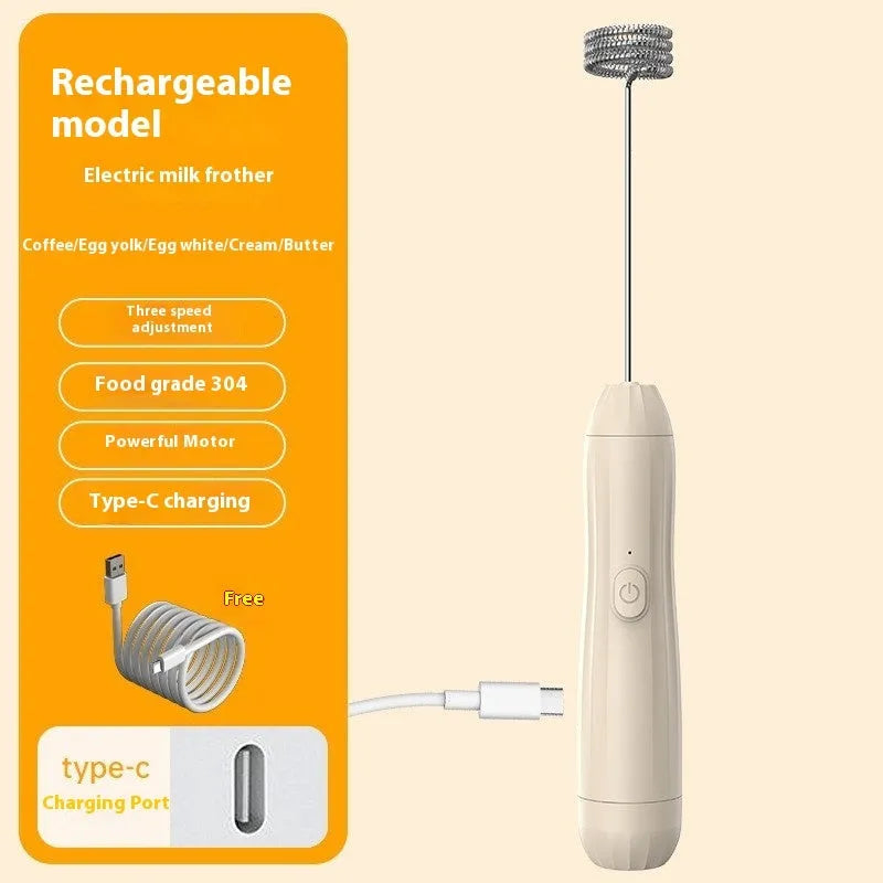 Compact black handheld USB rechargeable milk frother with stainless steel whisk on a kitchen counter.