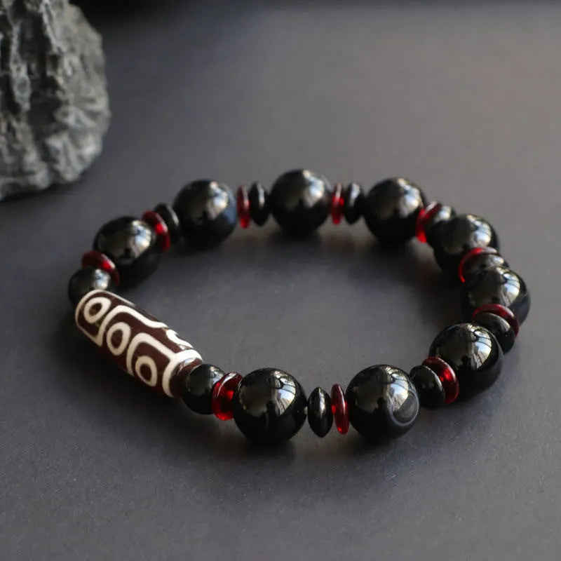 Close-up of a hand-woven black agate bracelet with 11mm geometric beads featuring traditional dzi patterns.