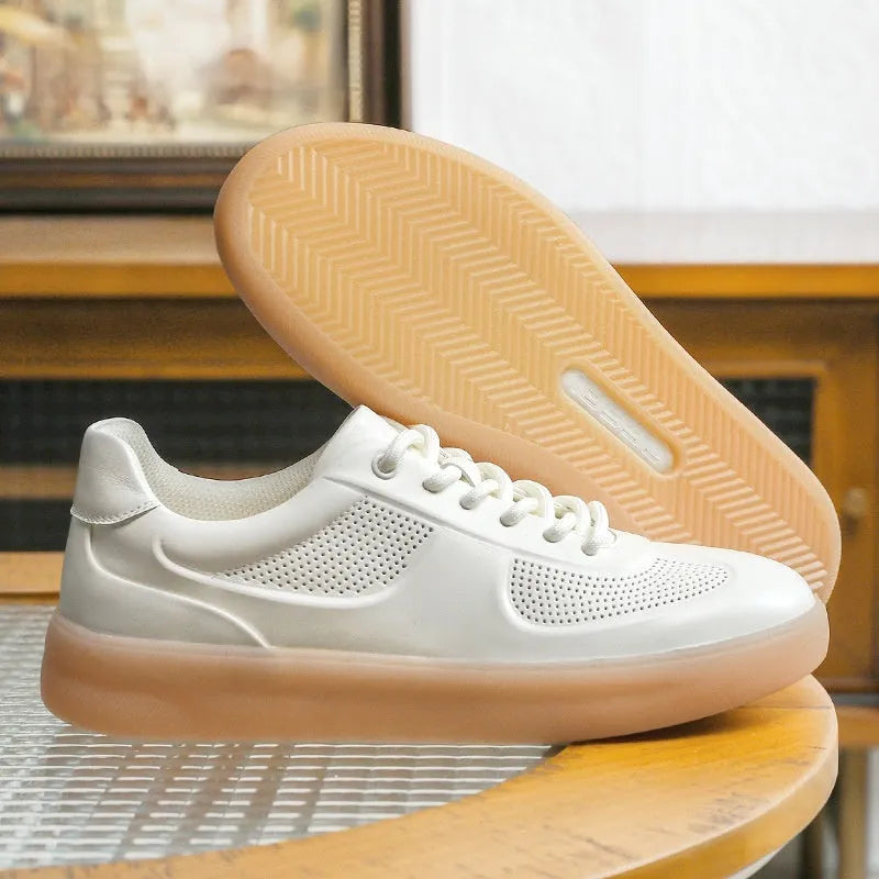 white perforated leather casual training shoes with rubber sole and front lace-up on flat surface