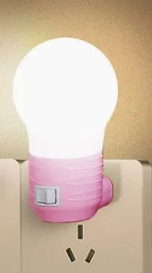 Plug-in bedside baby night light in white, blue, or pink shell with round design on a table