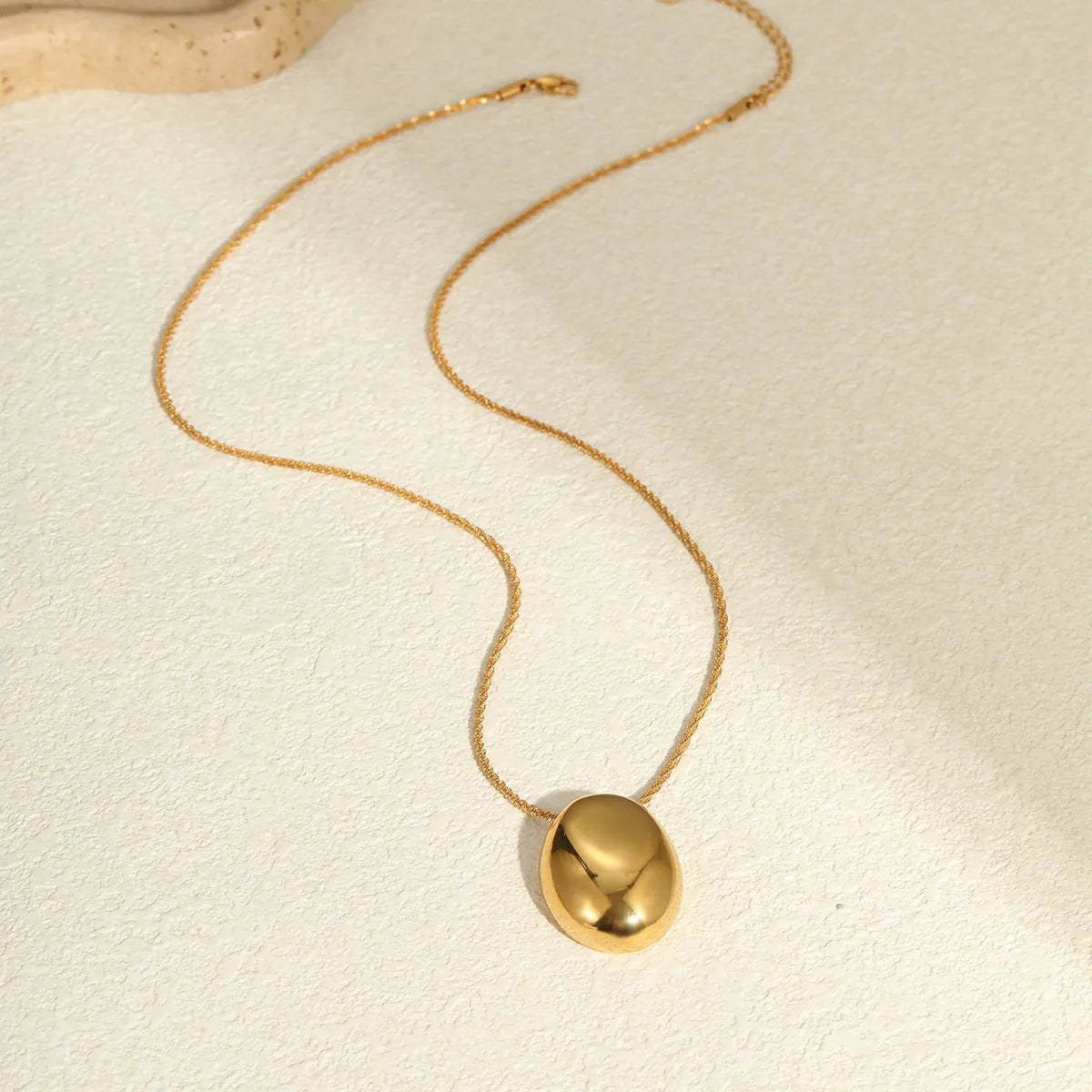 Gold geometric pendant necklace on a model, showing the adjustable chain length.