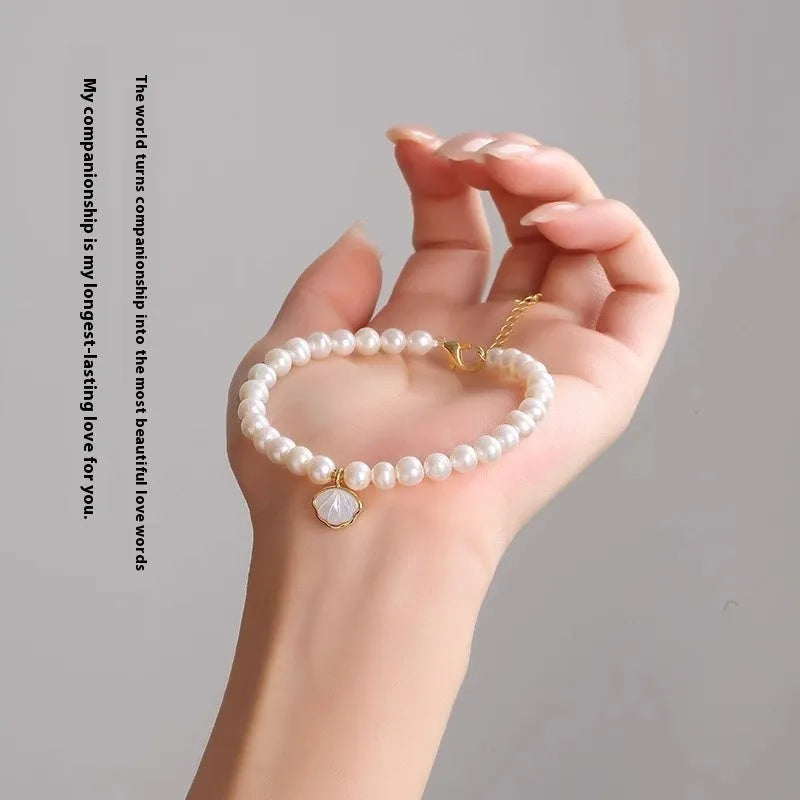 Women's freshwater pearl bracelet with fan-shell alloy clasp in 16cm size on wrist.